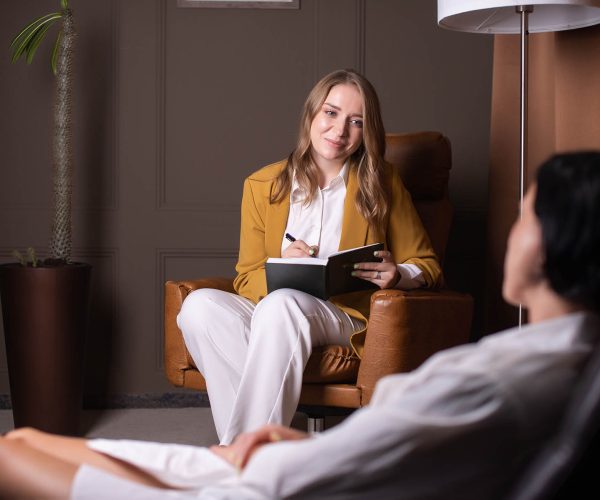 A female psychologist sits in a chair and listens to a client